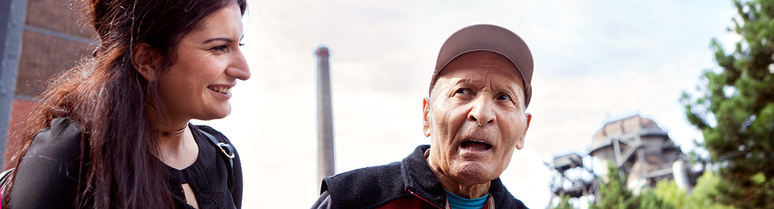 Eine junge Frau und ein alter Mann unter freiem Himmel